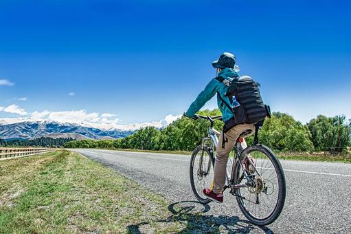 青空の下自転車を漕ぐ男性